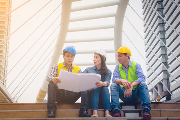 Working engineer. They are talking and plant for work with equipment beside building background. woman talking with a man plant for work. They sitting  on staircase. Photo concept for engineering.