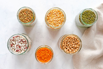 Open glass jars full of assorted dried legumes