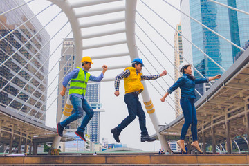 Working engineer. They  are jump in to sky and smile  mean teamwork  and spirit beside  building background. Photo concept for engineering  and team work.