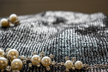 Women's metal jewelry made of pearls. Silver accessory for girls on a silver fabric background,...