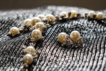 Women's metal jewelry made of pearls. Silver accessory for girls on a silver fabric background,...