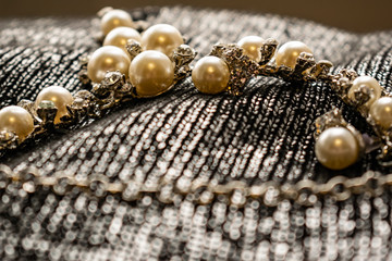 Women's metal jewelry made of pearls. Silver accessory for girls on a silver fabric background,...