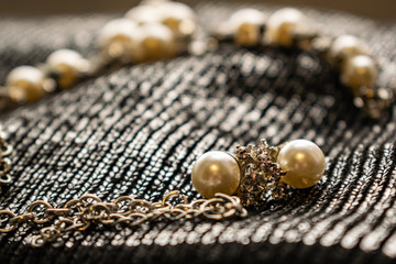 Women's metal jewelry made of pearls. Silver accessory for girls on a silver fabric background,...