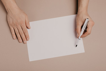 Hands writing on paper blank a4 size on grey background.