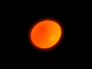 Illuminated egg isolated on black background. Backlight. Light penetrates the golden egg in dark. Easter