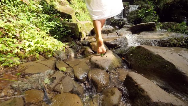 Attractive Girl in White Dress Walking Barefoot to Small Waterfall in Tropical Rainforest Jungle. Carefree Lifestyle Travel 4K Slowmotion Footage. Bali, Indonesia.