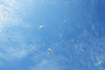 Paragliders are circling in an ascending current above the mountain Sarangkot. Blue sky, multi-colored wings.