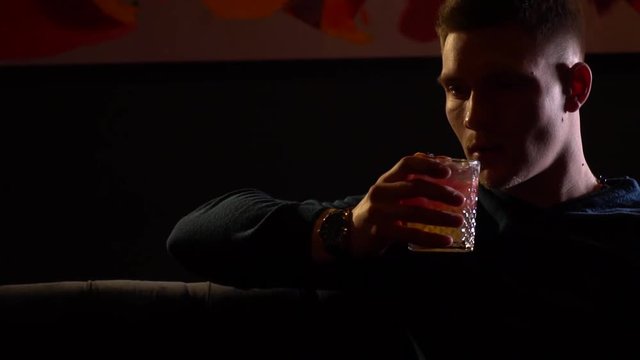 Young man sitting at the bar and drinking his cocktail