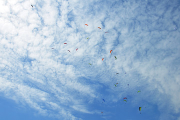 Paragliders are circling in an ascending current above the mountain Sarangkot. Blue sky, multi-colored wings.