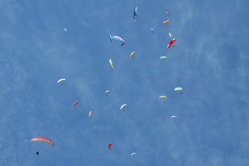 Paragliders are circling in an ascending current above the mountain Sarangkot. Blue sky, multi-colored wings.