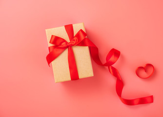 Gift box with red ribbon in trendy color of 2019 living coral background, concept of Valentine's, anniversary, mother's day, copy space, top view.