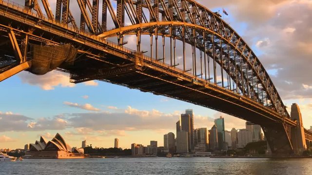 Day to Night timelapse of the Sydney Harbour Bridge and the Opera House during sunset in summer time, Australia.