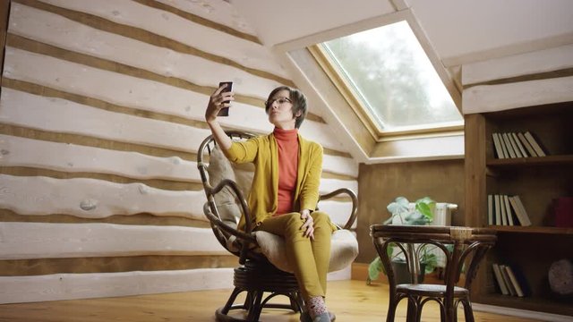 Adult pretty woman in glasses takes selfshot on attic