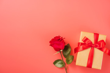 Gift box with red ribbon and rose in trendy color of 2019 living coral, concept of Valentine's, anniversary, mother's day, copy space, top view.