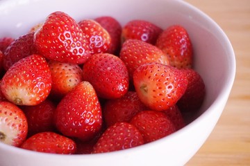 Strawberries in white ceramic bowl. Fresh nice strawberries on wooden table.