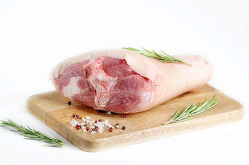 Uncooked pork knuckle on a wooden tray. Rosemary, salt and pepper for pickling shank. White background. Close-up.