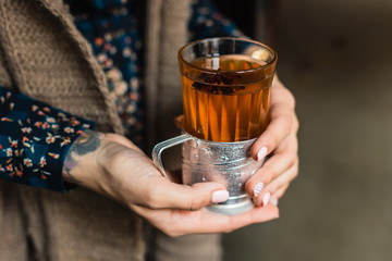 A glass with hot grog in woman's hands