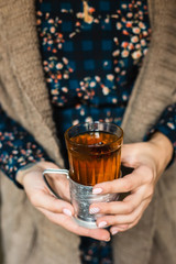 A glass with hot grog in woman's hands