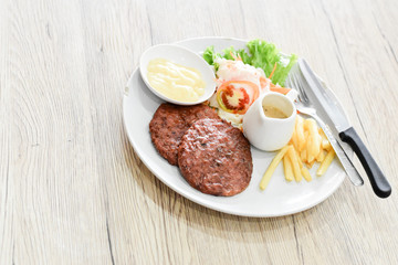 Beef steak, salad and french fries on a vintage wood background