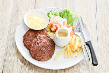 Beef steak, salad and french fries on a vintage wood background