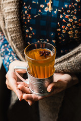 A glass with hot grog in woman's hands