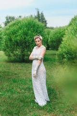 Colorful photography of young posing woman wearing knitted long white dress.  Outdoors image