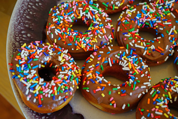Fresh donuts with chocolate icing and colorful sprinkles