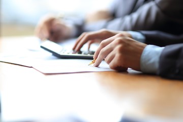 Close up of businessman or accountant hand holding pencil working on calculator to calculate financial data report,