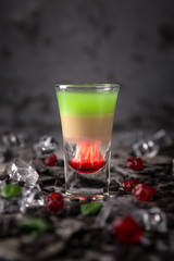 Alcoholic Hiroshima cocktail in shot glass (shooters). Cool drink from strong absinthe, whiskey and sweet liqueurs. 