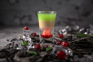Alcoholic Hiroshima cocktail in shot glass (shooters). Cool drink from strong absinthe, whiskey and sweet liqueurs. 