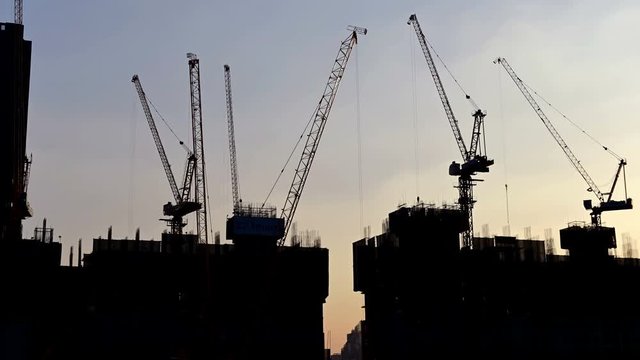 4K Time lapse of silhouette view tower cranes at construction site