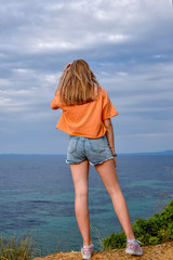 Fototapeta na wymiar Girl standing on a cliff above the sea