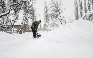 Man with a shovel cleans the track from the snow