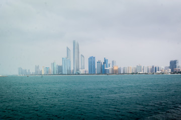 Obraz premium Beautiful shot of Abu Dhabi city skyline towers and beach on a cloudy day