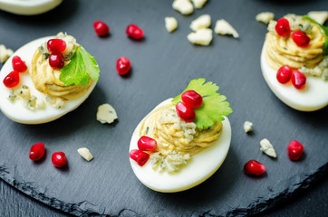 Blue cheese deviled eggs with pomegranate and fresh parsley leaves
