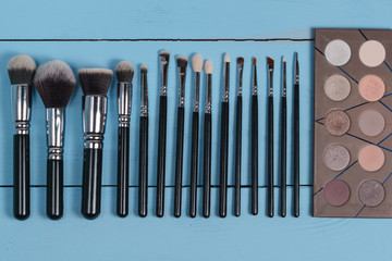 Set of make up brushes / brush collection on blue wooden background. Close up. Top view. Flat lay. Mock up. texture