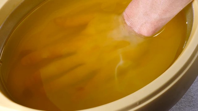 Close up slow motion shot of unrecognizable woman putting hand into paraffin bath taking care of hands skin