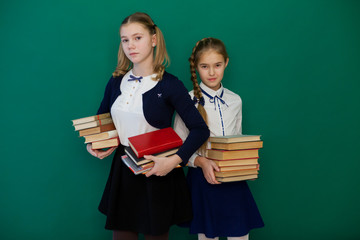 two schoolgirls girls on the lesson at the Blackboard with books