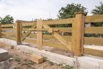 Wooden gates for vehicle entry into the house. Fence in ranch style.