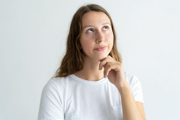 Pensive young woman looking upwards. Pretty lady touching chin. Contemplation concept. Isolated front view on white background.