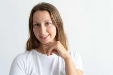 Smiling beautiful young woman posing at camera. Girl touching face and looking at camera. Pretty woman concept. Isolated front view on white background.