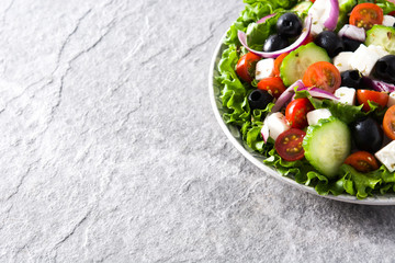 Fresh Greek salad in Plate with black olive,tomato,feta cheese, cucumber and onion on gray background. Copyspace