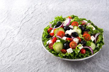 Fresh Greek salad in Plate with black olive,tomato,feta cheese, cucumber and onion on gray background. Copyspace