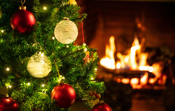 Christmas Tree Close Up On Blurred Burning Fireplace Background