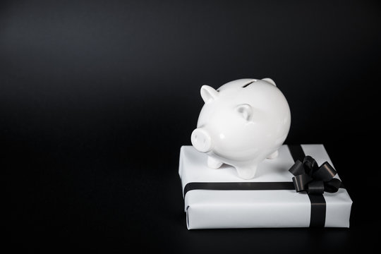 Piggy bank style money box and gifts isolated on black a background.