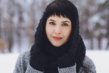 Young beautiful brunette girl in a sweater in the winter snowy forest