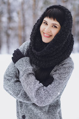 Young beautiful brunette girl in a sweater in the winter snowy forest