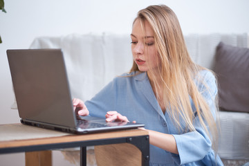 young beautiful woman at home drinking coffee and using a laptop for work. freelance for students