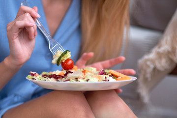 young woman is eating salad at home, diet concept. disgruntled person, depression from having to diet, lack of fat in the diet.