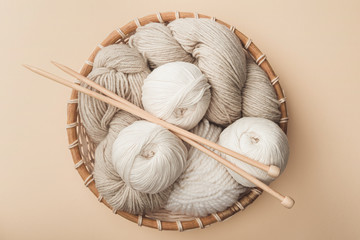 Fototapeta na wymiar top view of yarn and knitting needles in wicker basket on beige background
